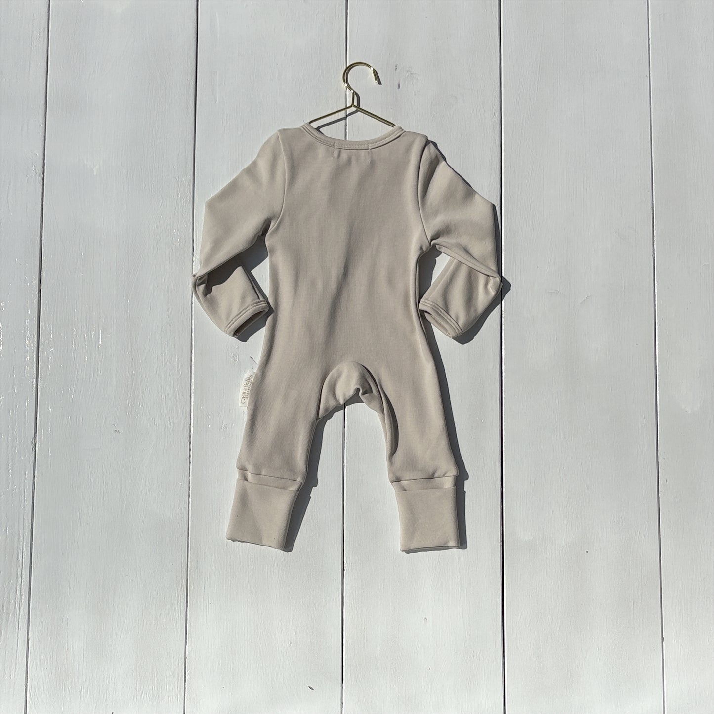 Dusty grey newborn baby romper on a hanger against a wooden background