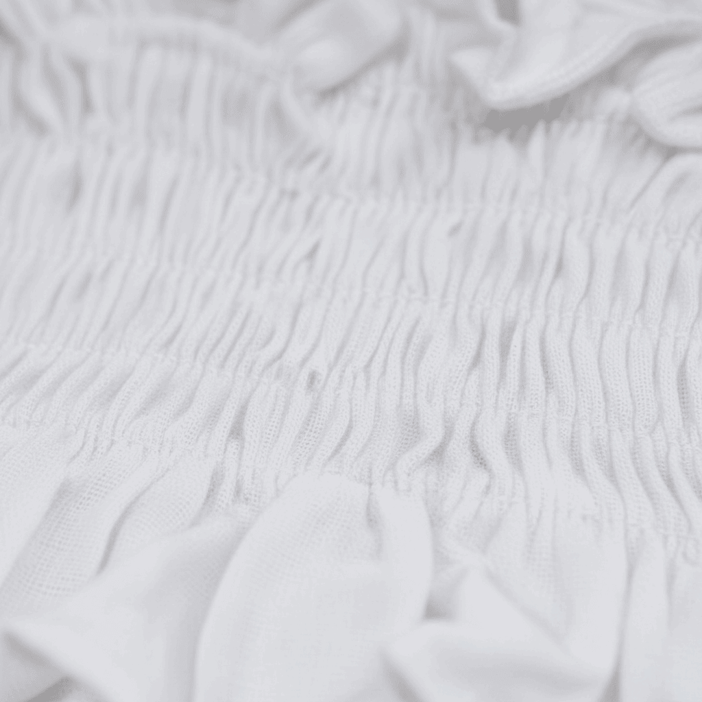 Soft white organic baby clothing with delicate smocked texture