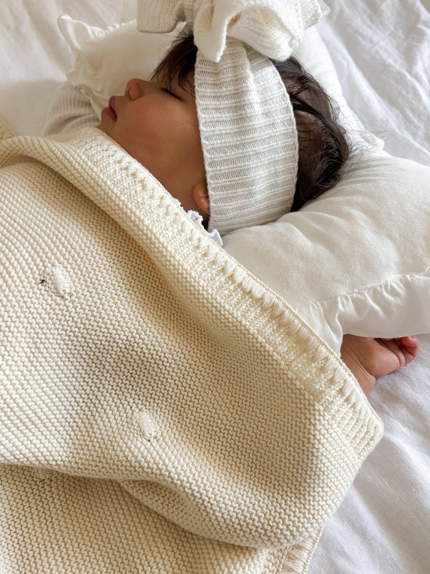 Close Up Organic soft knitted baby blanket wrapped around newborn wearing striped organic headband by Casita Bebes.