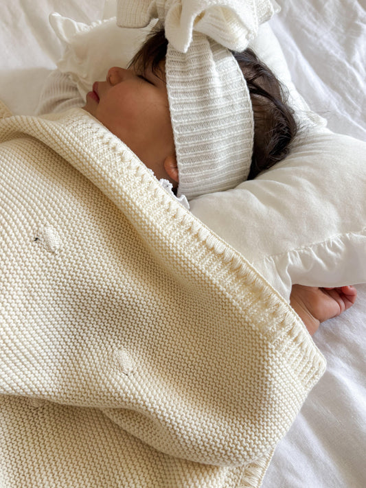 Close Up Organic soft knitted baby blanket wrapped around newborn wearing striped organic headband by Casita Bebes.