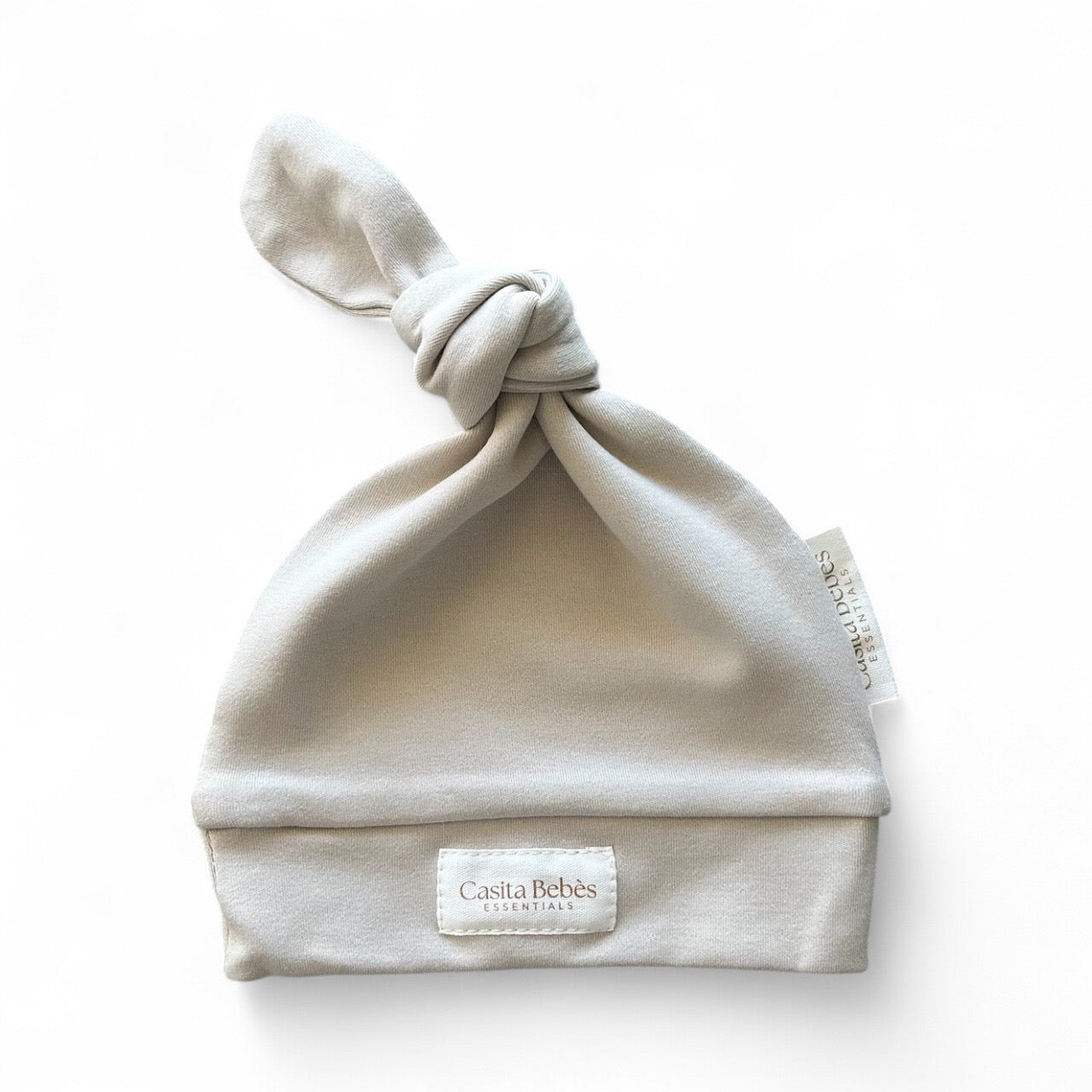 Dusty Grey Newborn beanie with a knot on top and 'Casita Bebes' label on a white background