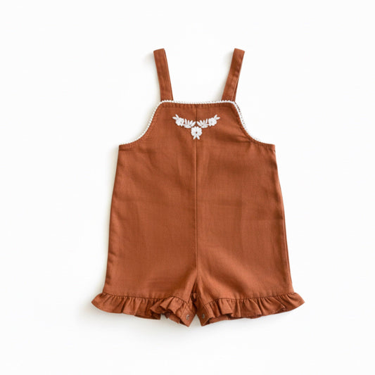 Rust brown organic baby playsuit with white flower embroidery and ruffled hems, certified organic.