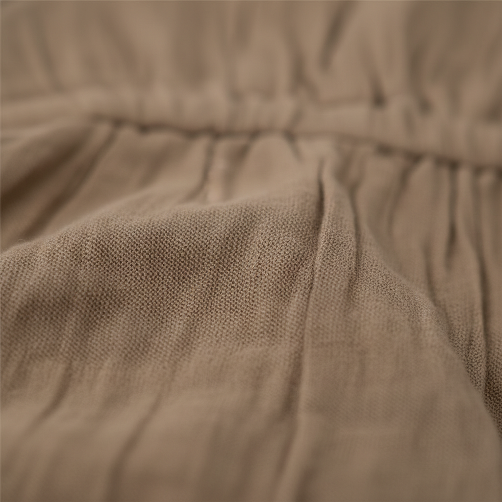 Close-up of soft khaki organic cotton fabric with gentle gathers on Mamīta Malani jumpsuit for baby clothing by Casita Bebes.