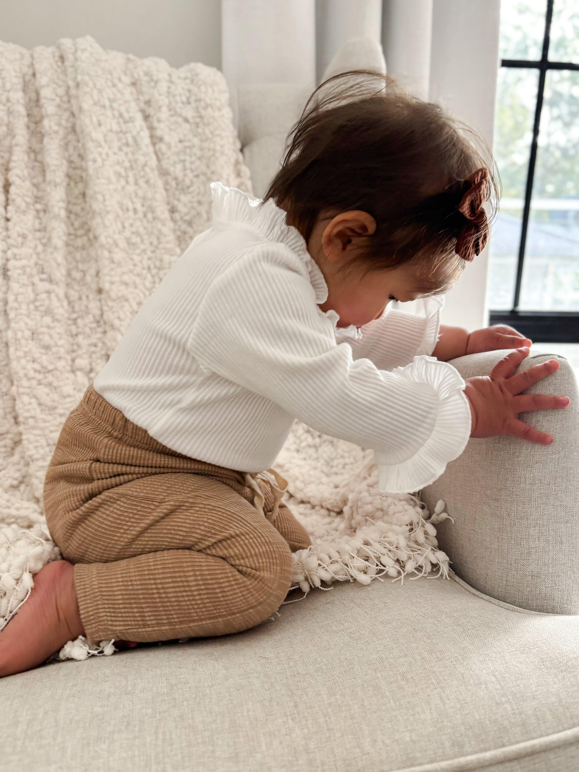 Baby wearing organic cotton textured brown pants from Casita Bebes Essentials Collection.