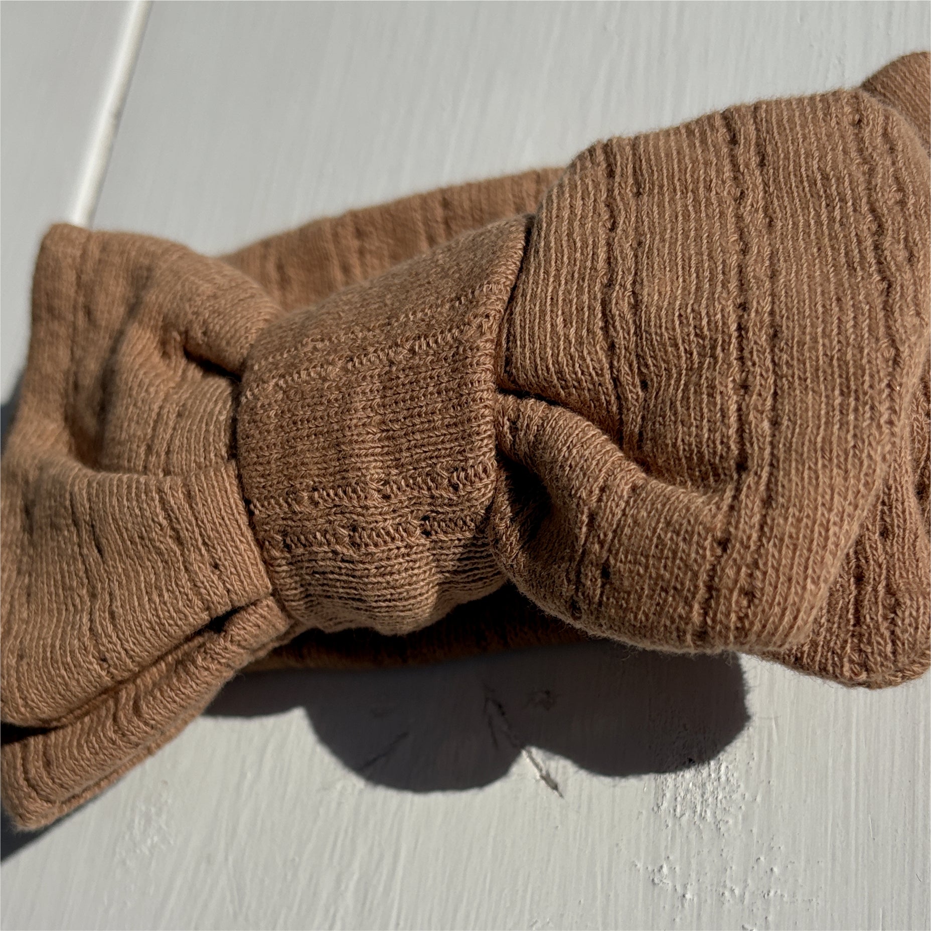 Close Up Brown knitted headband on a light wooden surface