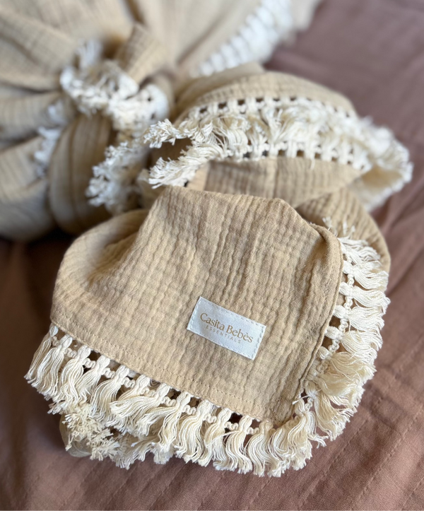 Neutral Beige baby blanket with tassels details on a brown surface with Casita Bebes brand