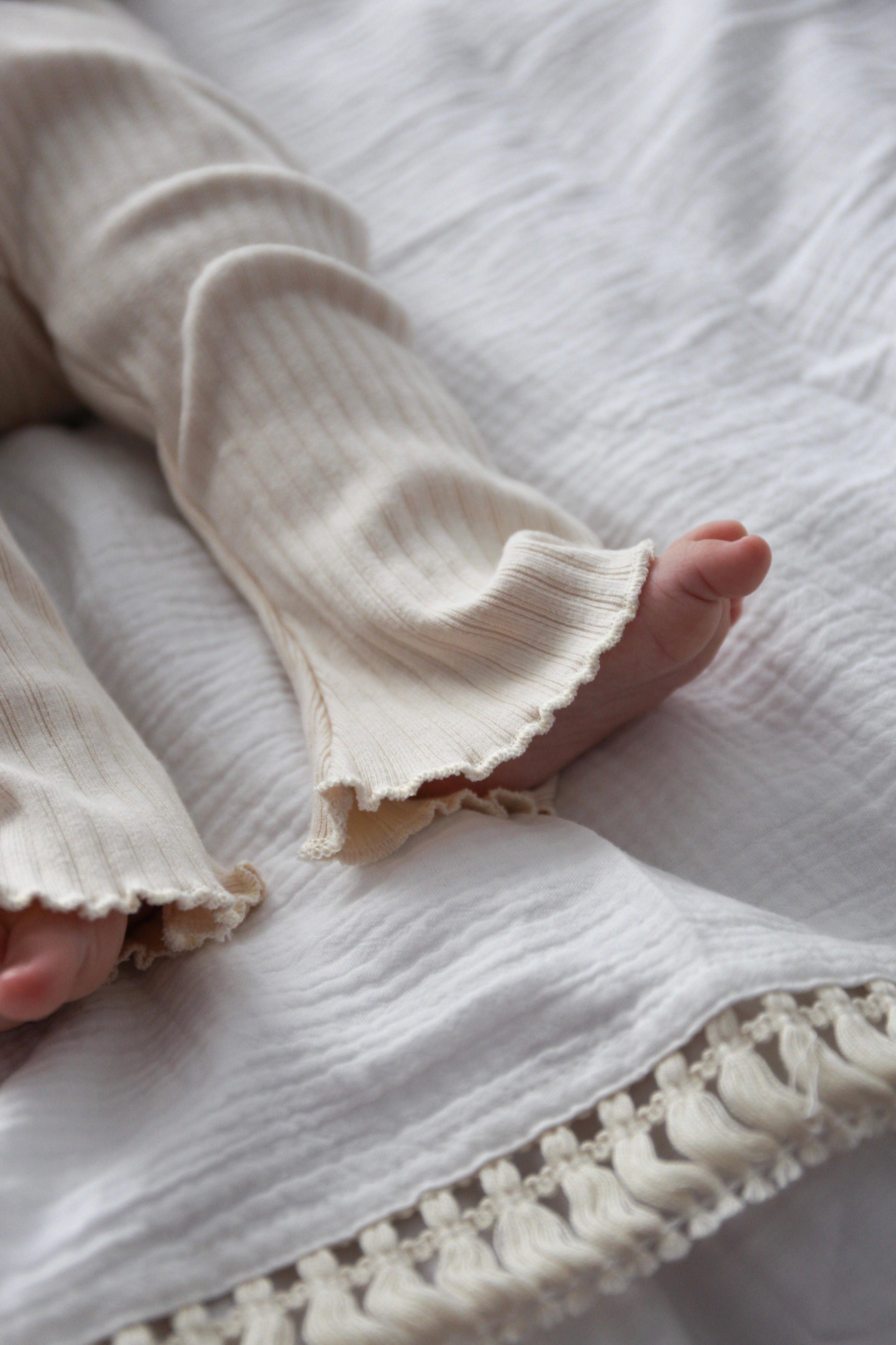 Close-up of a baby's Mamīta Flared Pants on essentials tassel blanket