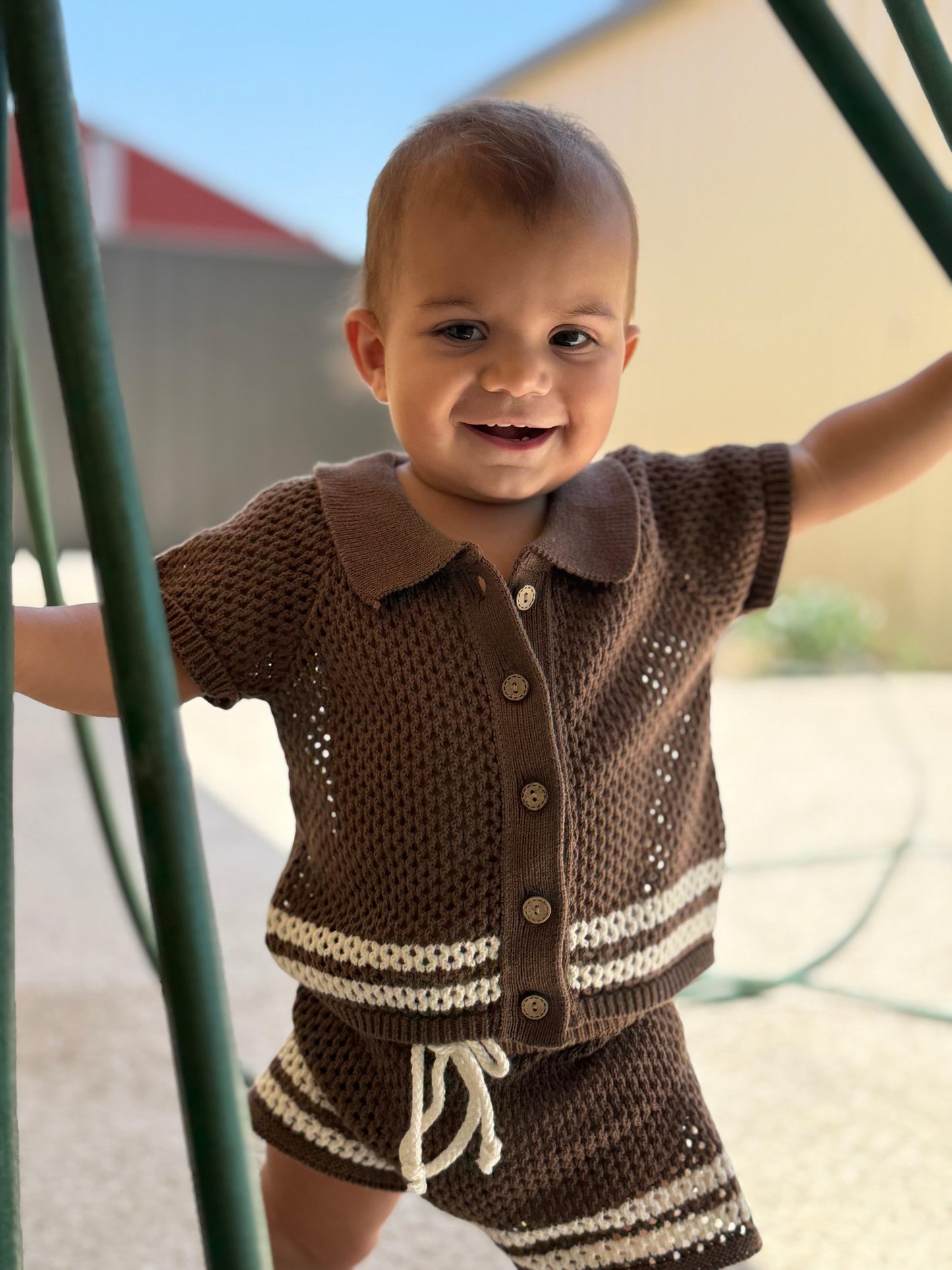 Baby wearing certified organic dusty brown knit swim top with white trim and buttons, Casita Bebes.