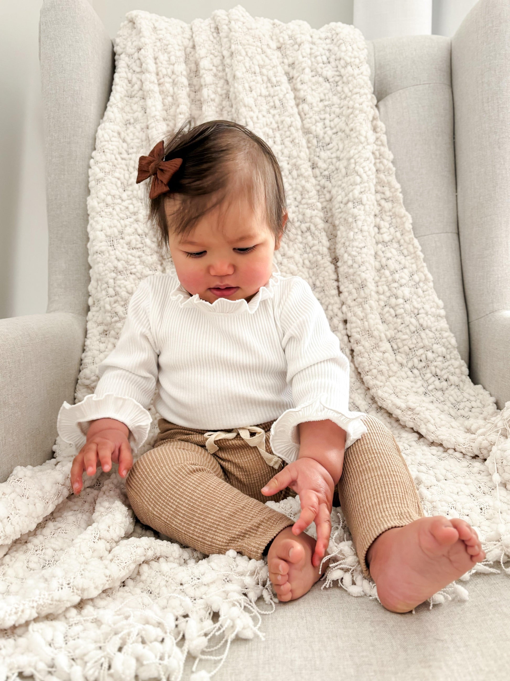 Baby wearing beige organic cotton textured pants from Casita Bebes Essentials Collection.