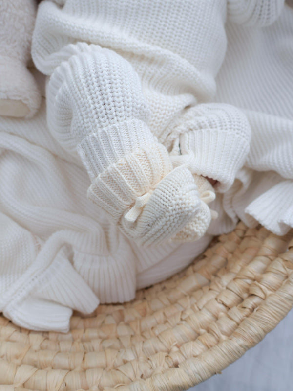 White knitted fabric  booties on a woven surface Casita Bebes brand