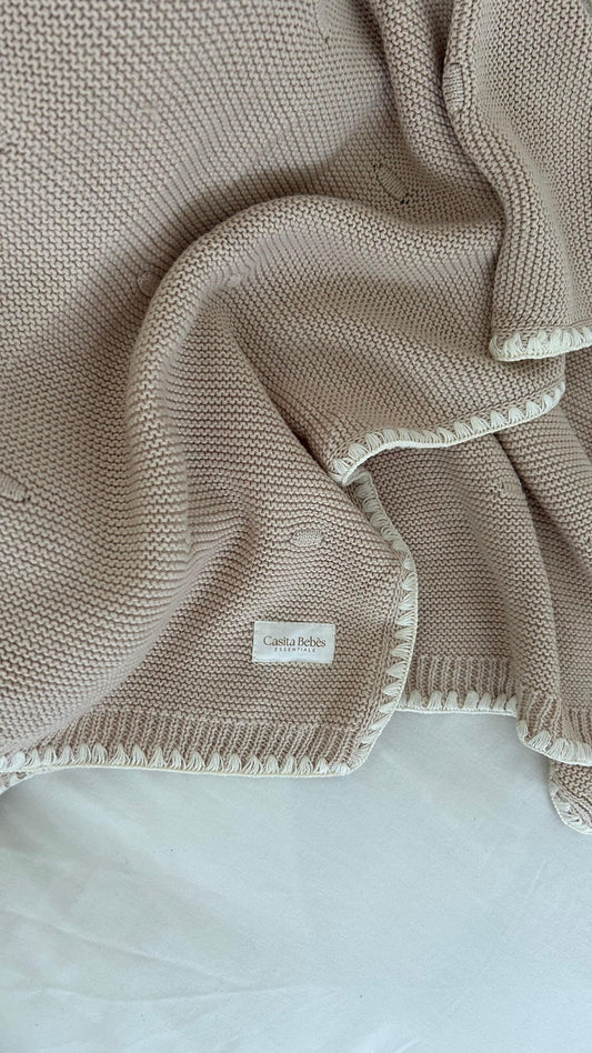 Dusty brown organic knitted baby blanket with soft texture and stitched edges, Casita Bebes tag visible.