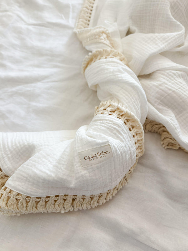 Organic cotton tassel blanket with certified label, soft neutral tones, Casita Bebes branding.