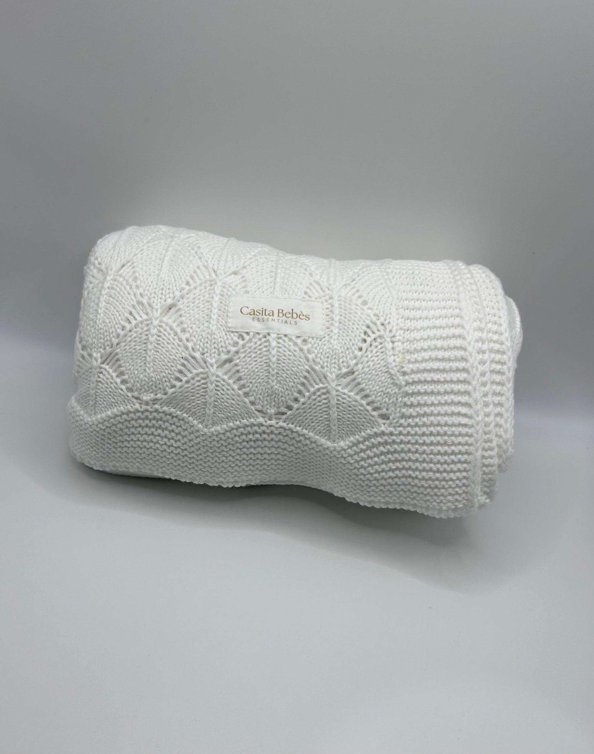 White knitted baby blanket  Casita Bebès Brand logo on a gray background