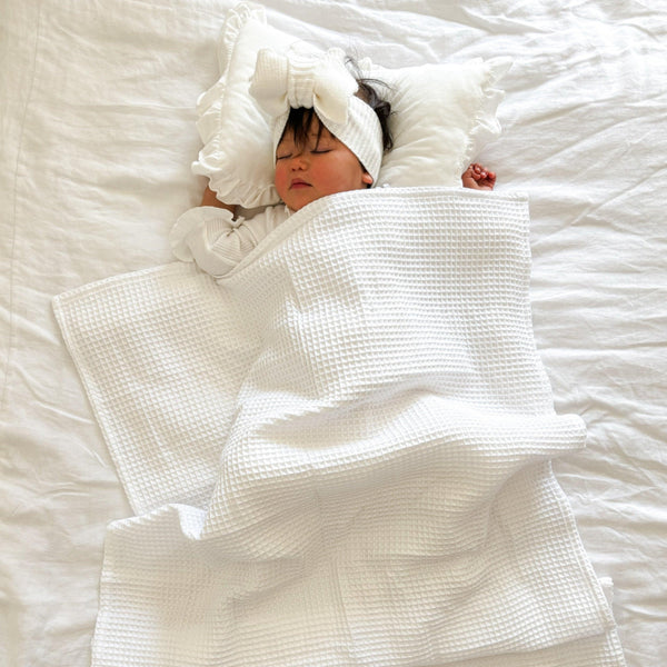 Newborn wrapped in organic certified Essentīals waffle baby blanket by Casita Bebes.