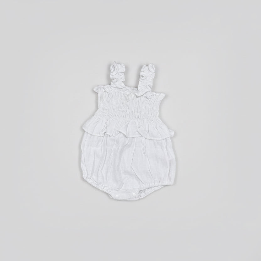 Flat lay White baby romper with ruffled details on a gray background