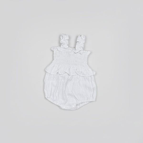 Flat lay White baby romper with ruffled details on a gray background
