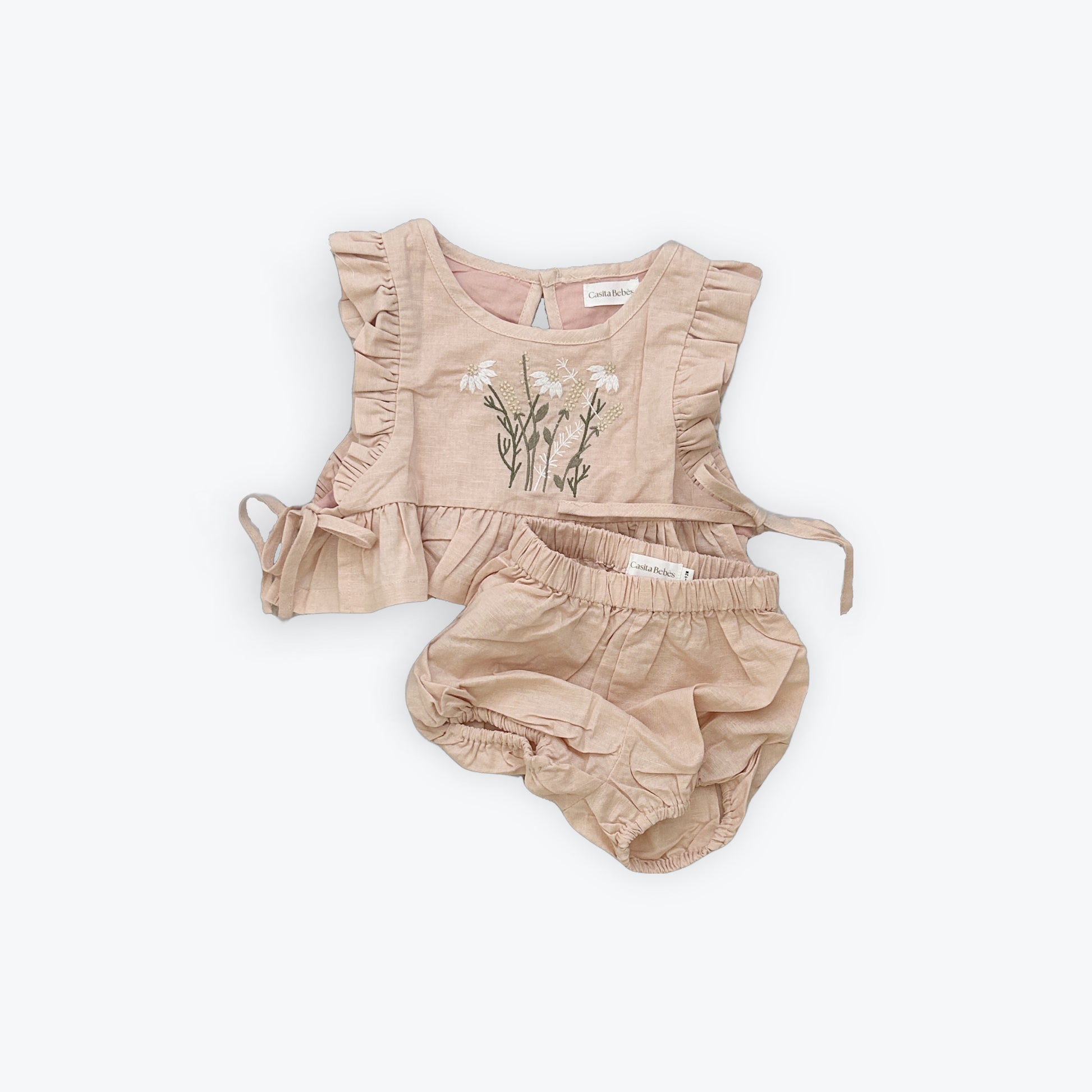 Baby girl flat lay outfit with ruffled top and bloomers on a white background