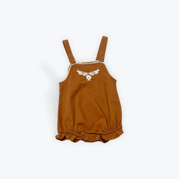 Flat lay Mamīta Siena Pinfore Brown baby romper with floral embroidery on a white background