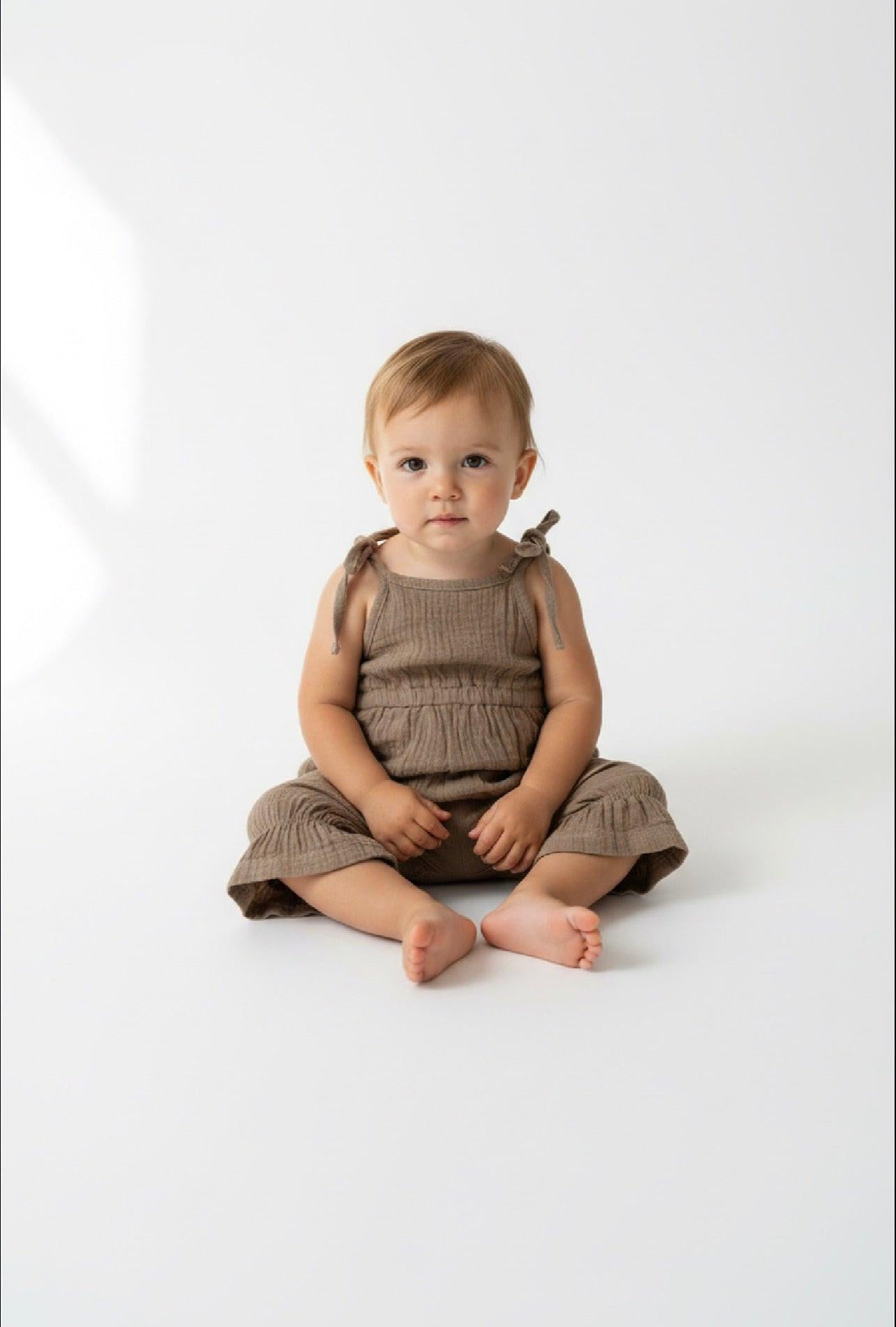 Organic cotton khaki jumpsuit on baby with tie shoulder straps from Casita Bebes.
