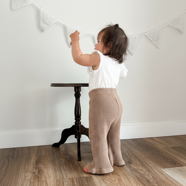 Baby wearing organic dusty brown knitted flared pants from Mamíta Collection.
