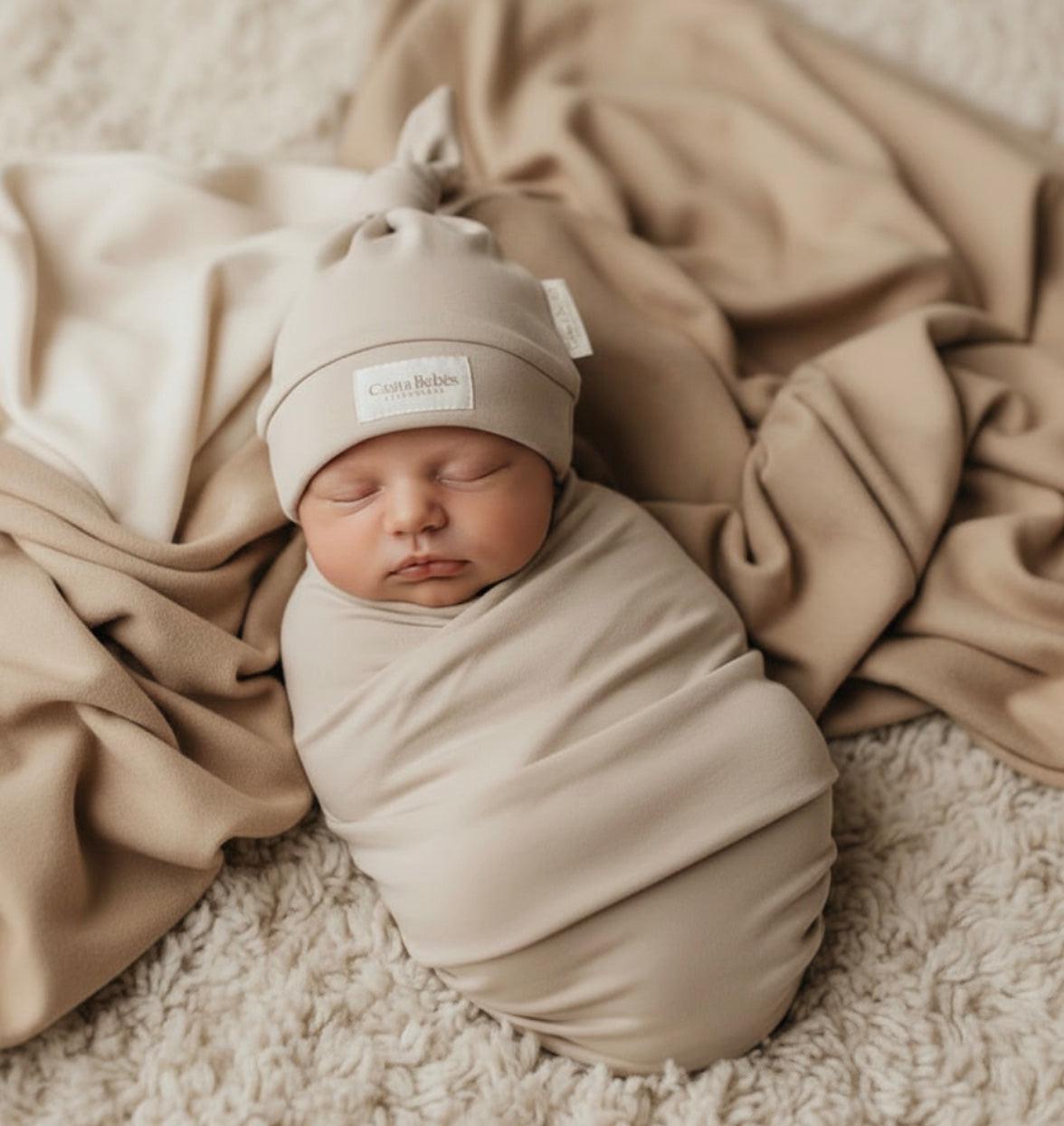 Sleeping baby wearing certified organic misty grey cotton beanie with top knot from Casita Bebes.