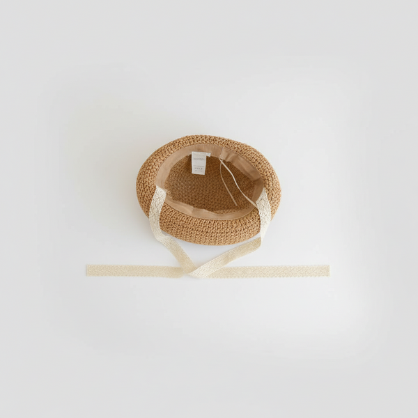 Woven straw toddler hat with a white ribbon on a light gray background