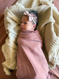 Newborn baby wrapped in a pink blanket with a yellow bow, lying on a textured yellow blanket.brand Casita Bebes