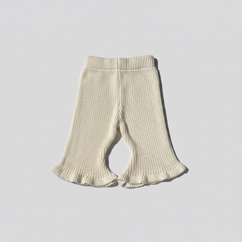 Beige knitted ribbed flared baby pants on a light wooden floor brand Casita Bebès