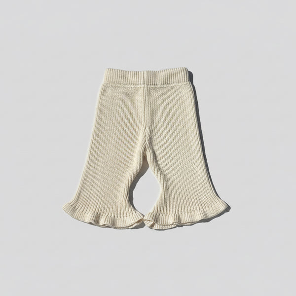Beige knitted ribbed flared baby pants on a light wooden floor brand Casita Bebès