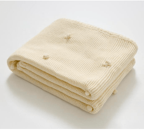 Folded beige Knitted Newborn blanket on a white background