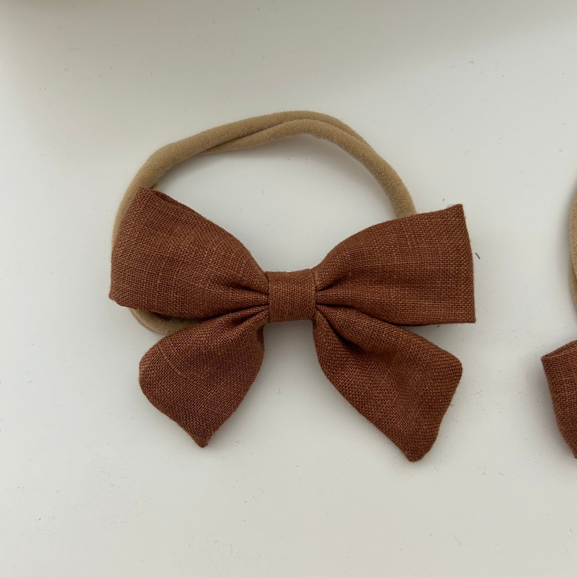 Brown fabric bow on a beige headband against a white background casita Bebès brand