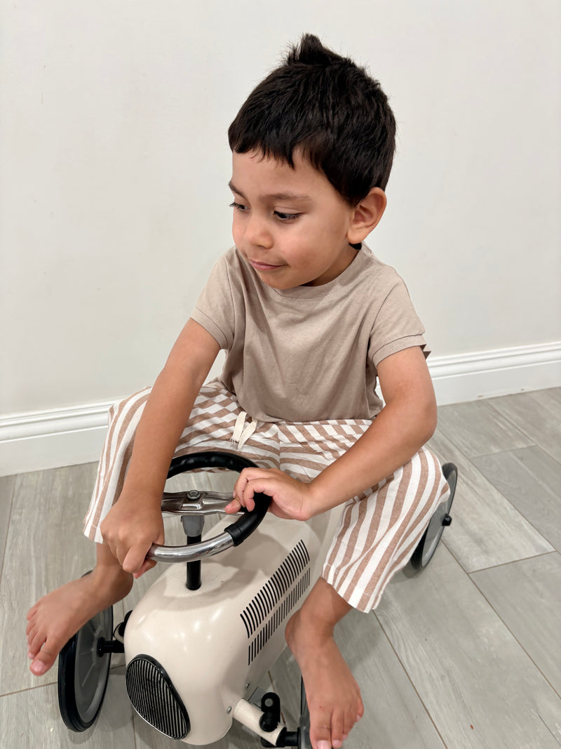 Child sitting on a toy car indoors with a plain background