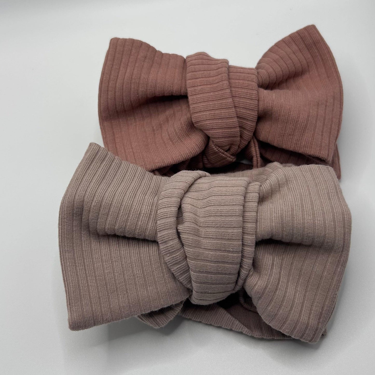 Two ribbed knit baby headbands in brown and beige on a white background