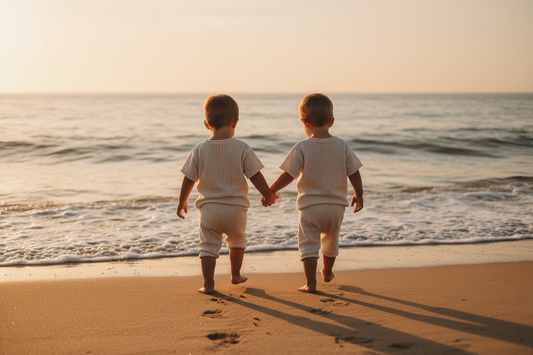 Two children holding hands on a beach at sunset. Brand Casita Bebes