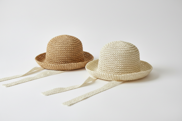 Two straw sun protection hats wide brim neutral  with ribbons on a white background 