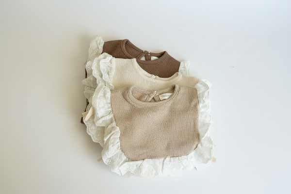 Three baby bibs with ruffled edges on a light background