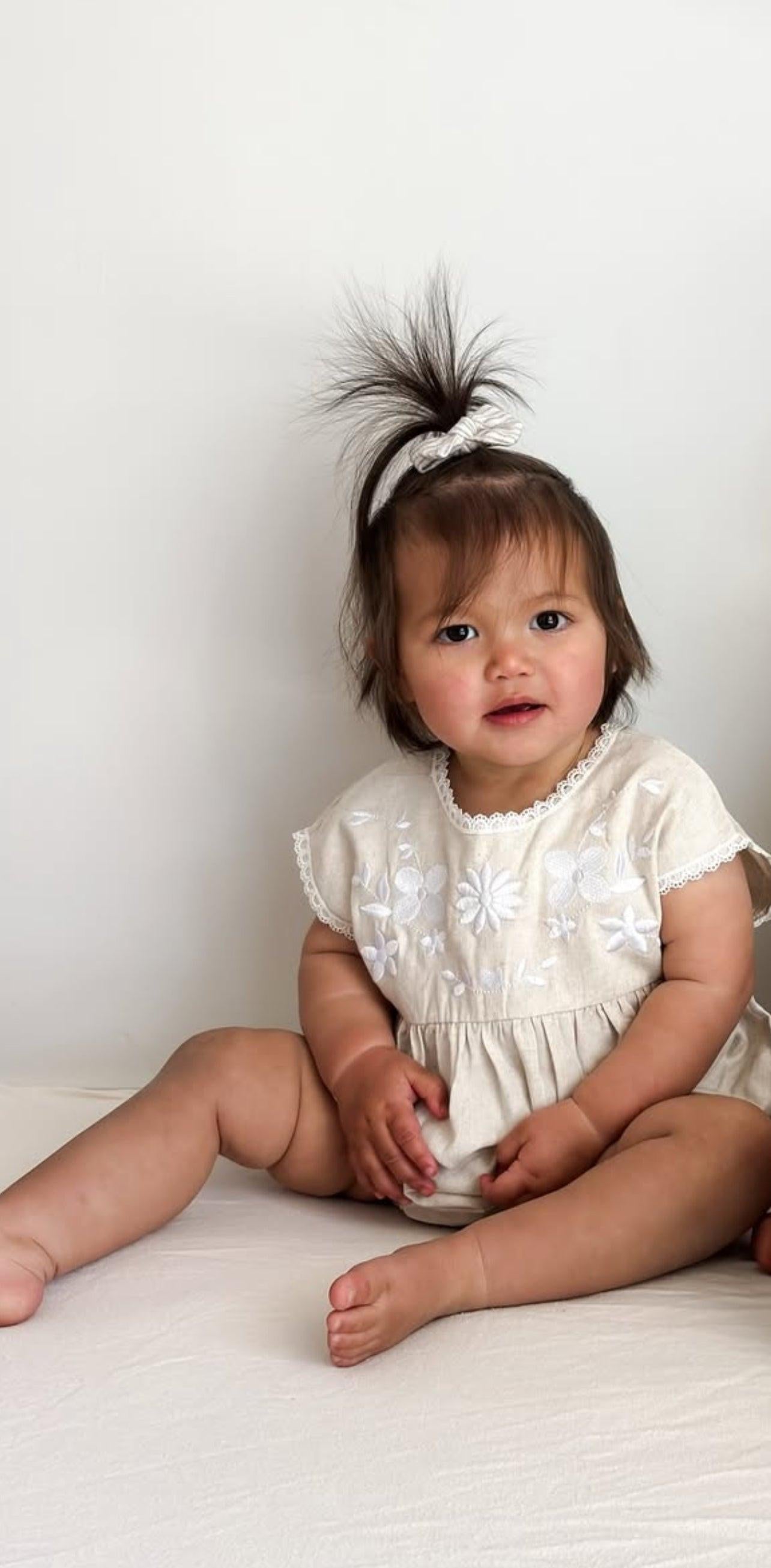 Organic cotton baby girl romper with short sleeves, delicate embroidery, and ruffle details.