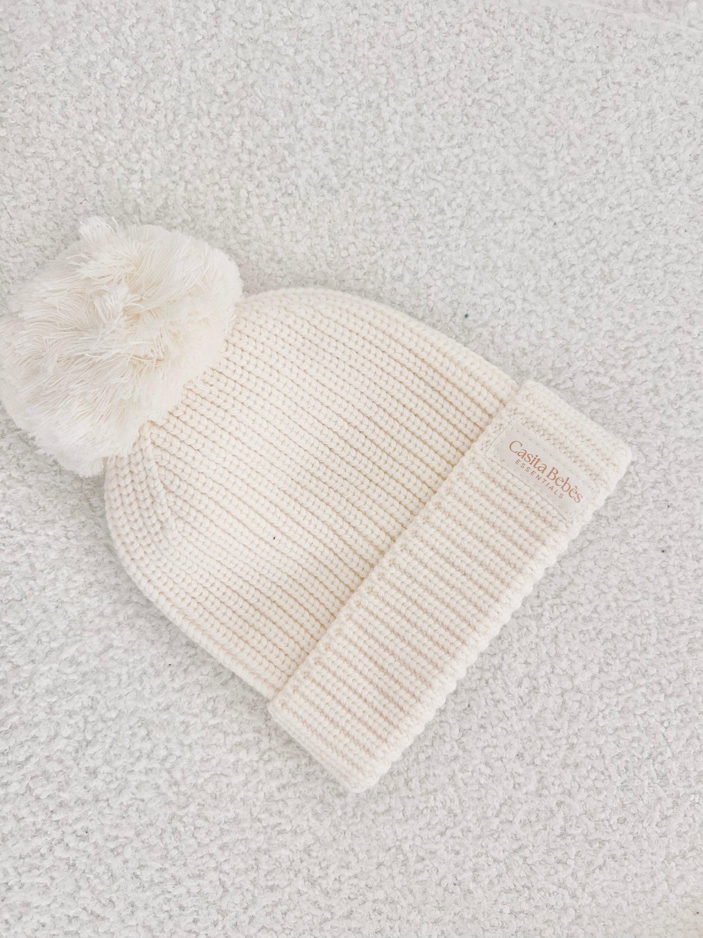 Cream organic cotton knitted baby beanie with pom-pom and folded cuff, certified organic.