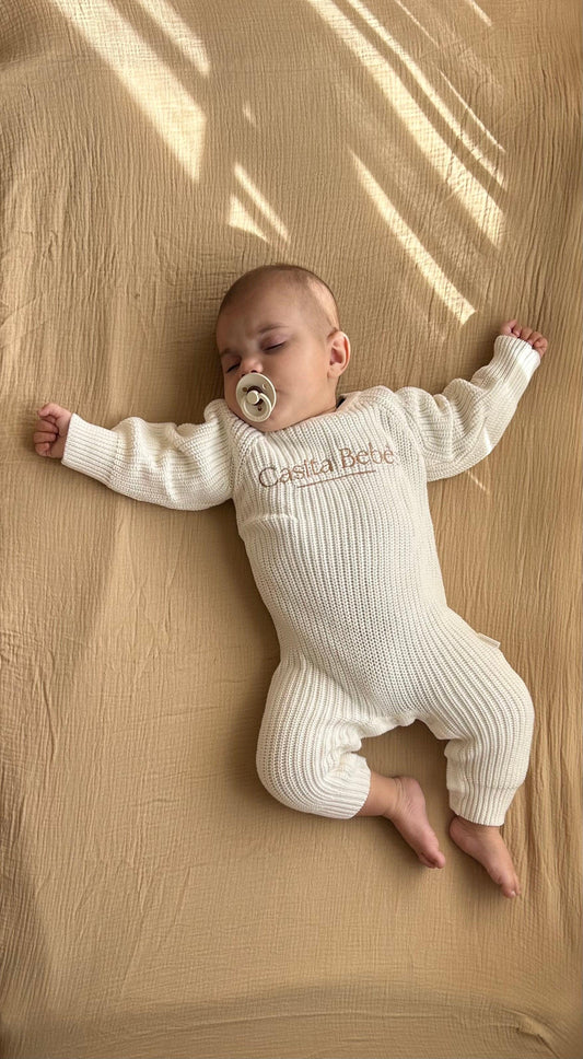 Newborn baby wearing organic certified beige knitted romper from Casita Bebes Essentials collection.