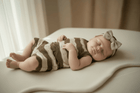 Newborn baby sleeping peacefully in striped organic knit onesie with bow headband, soft blanket