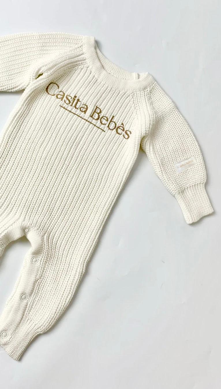 Cream organic cotton knitted baby romper with Casita Bebes embroidery, long sleeves, and ribbed texture.