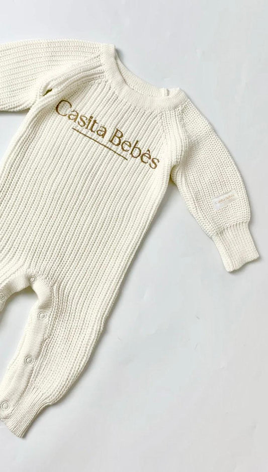 Cream organic cotton knitted baby romper with Casita Bebes embroidery, long sleeves, and ribbed texture.