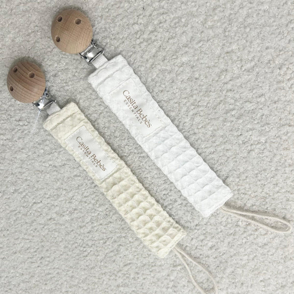 Two organic waffle-textured dummy holders in blanco and beige with wooden clips, certified organic baby accessories by.