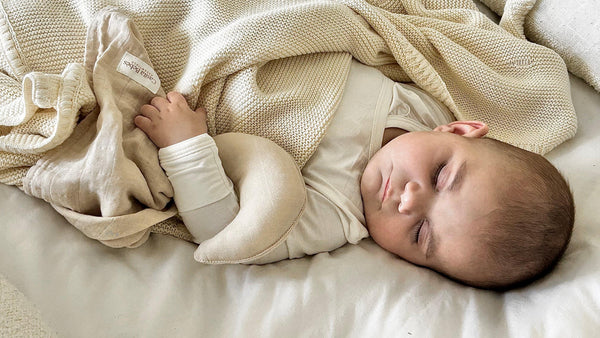 Sleeping baby wearing organic cotton clothing wrapped in a soft organic cotton comforter.