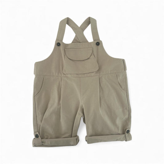Beige organic cotton toddler overalls with front pocket and buttoned rolled cuffs.