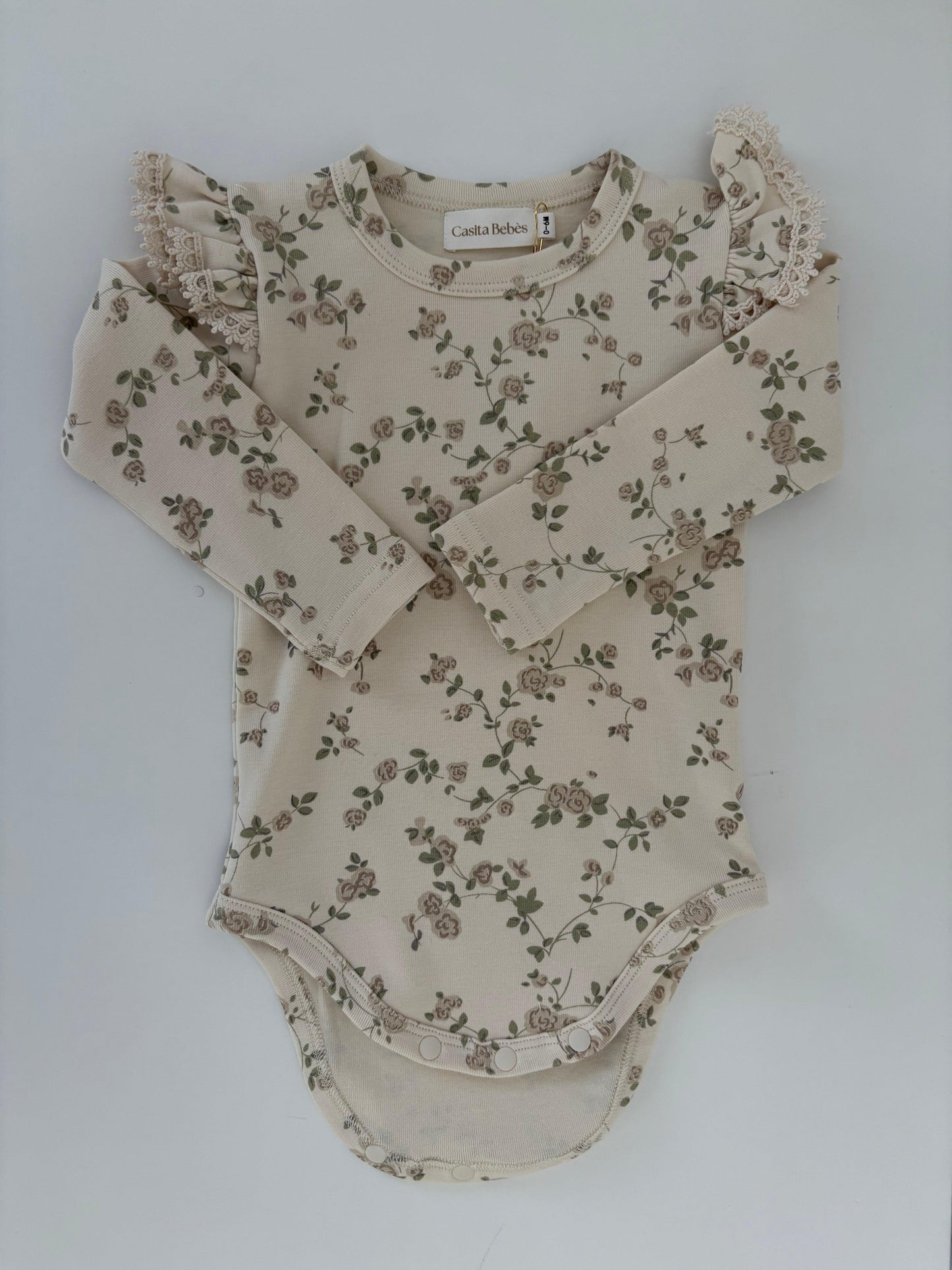 Organic cotton baby bodysuit with delicate floral print and ruffled shoulders by Casita Bebes.