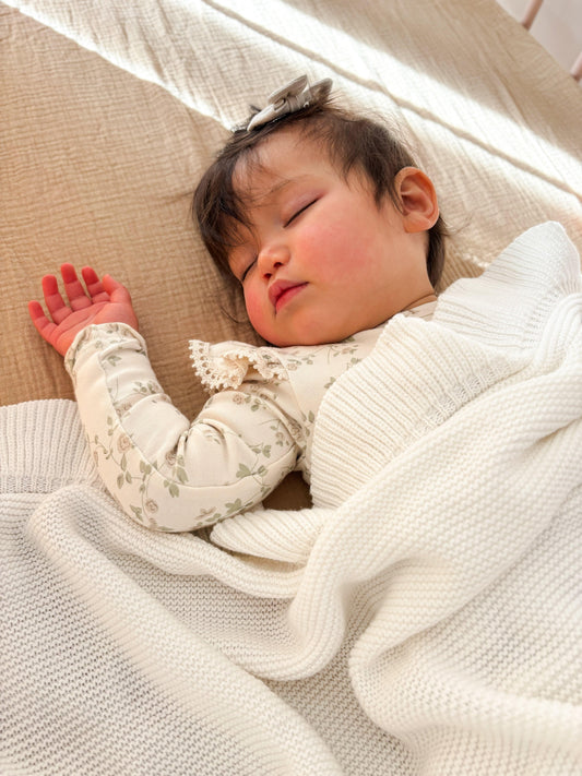Sleeping baby wrapped in certified organic cotton Essentīals cot sheet by Casita Bebes.