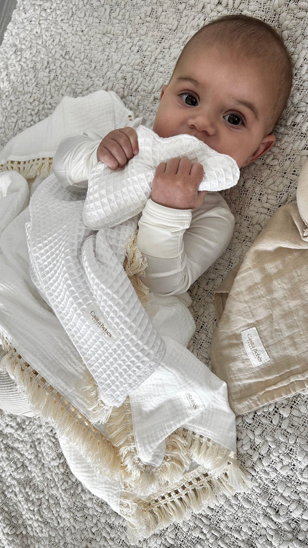 Baby wearing white organic waffle comforter with ruffle edges, certified organic baby clothing by Casita Bebes.