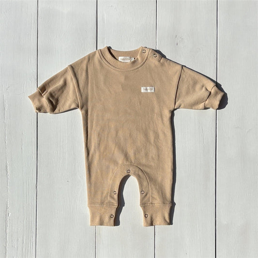 Organic tan baby romper from Casita Bebes with snap closures and certified organic fabric.