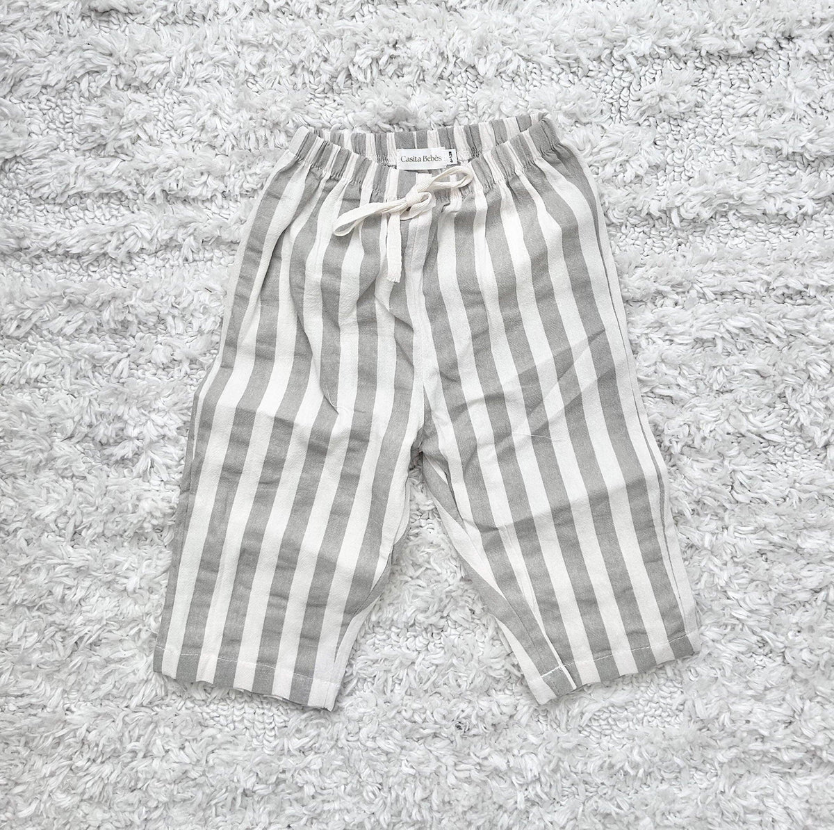 Gray and white striped baby pants on soft rug, organic cotton comfort